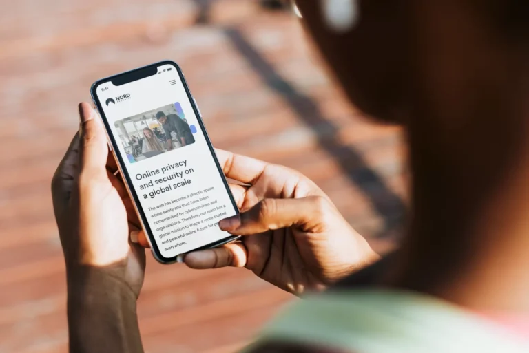 A hand holding a smartphone with the Nord Security mobile website